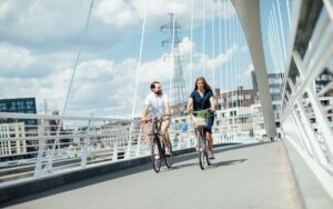 Man and young woman cycling across bridge on a cloudy day_Nefco-Nordic Green Bank