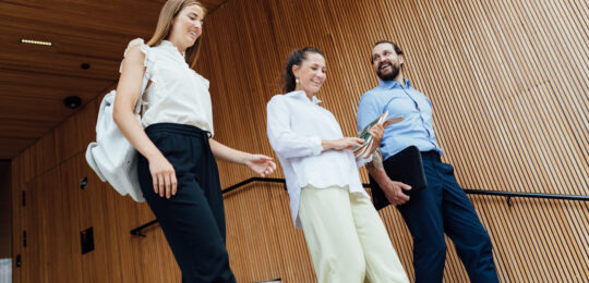 Men, woman and young girl going downstairs outside a building with wooden background_Nefco-Nordic Green Bank