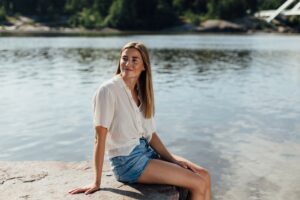 Young woman smiling sitting on a rock by the Baltic Sea_Nefco-Nordic Green Bank