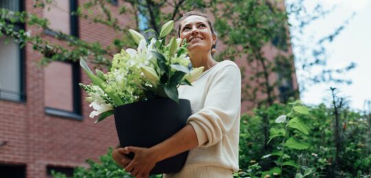 Woman carrying a pot with flowers in the garden_Nefco-Nordic Green Bank