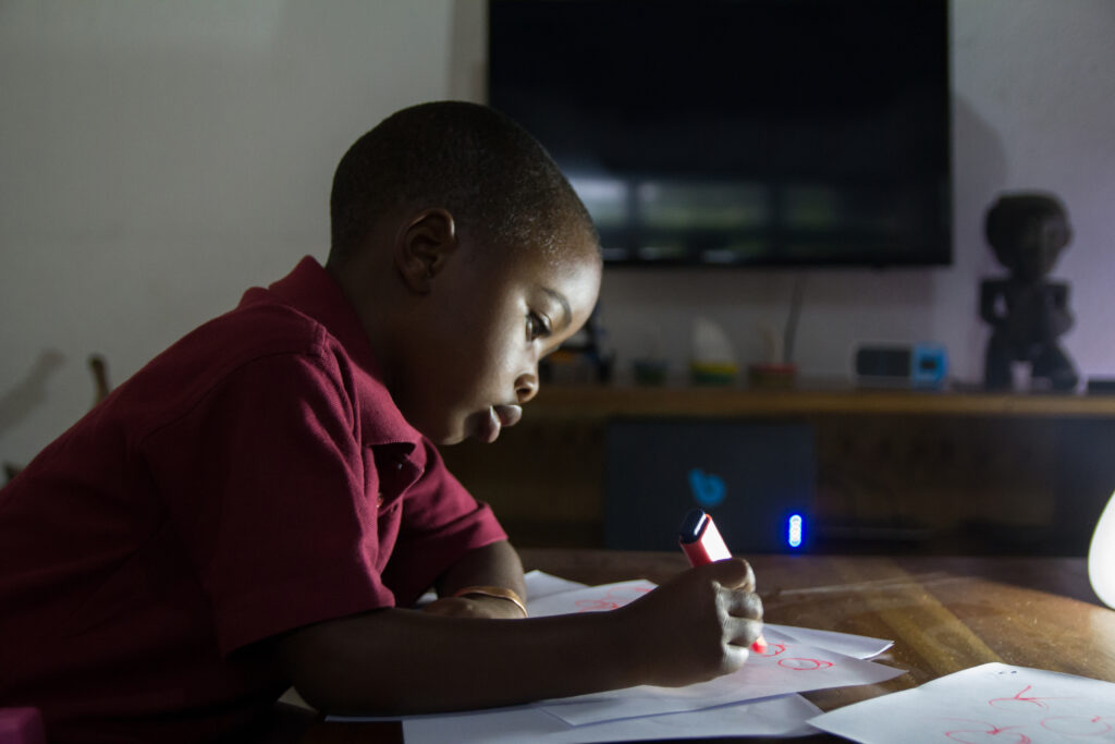 Child studying at night with the help of Bboxx solar-home system appliance. Photo: Bboxx