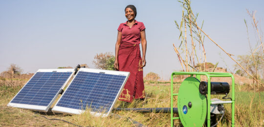 Female tomato farmer in Kabwe, Zambia, cultivating and irrigating the land with an off-grid solar-powered water pump.
